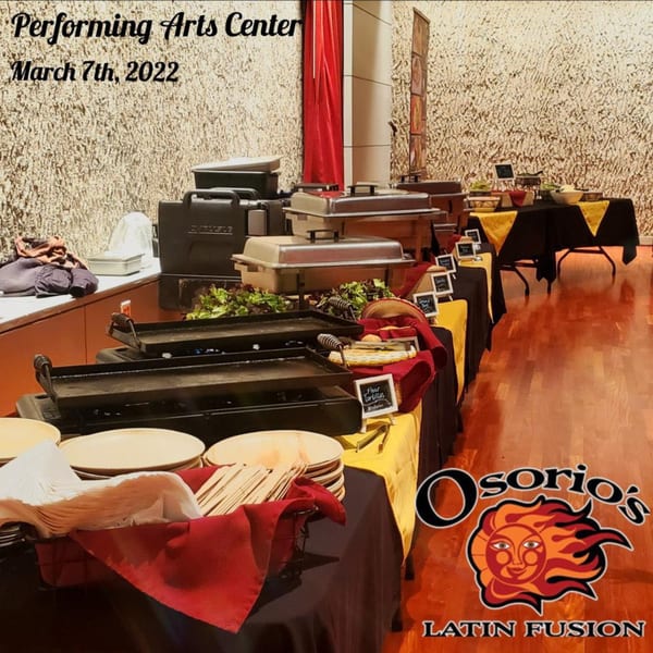 Osorio's Latin Fusion catering setup with chafing dishes, griddles, and serving ware on black and yellow tables.
