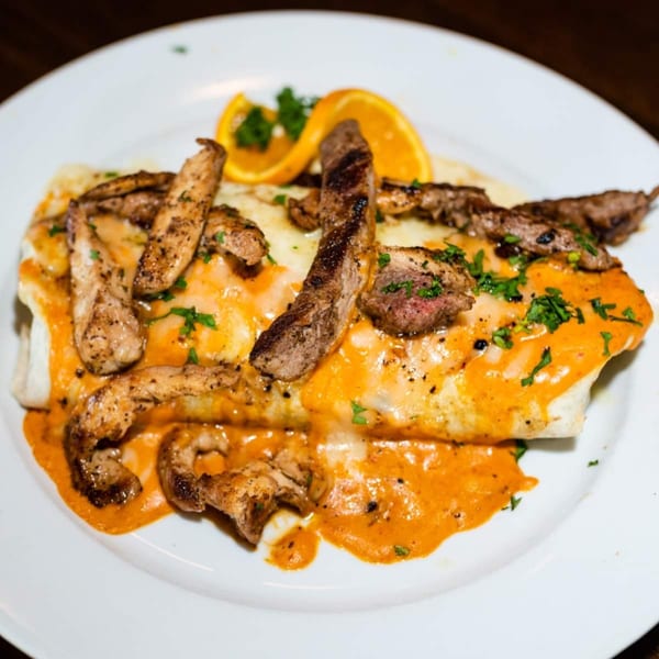 Osorio's Latin Fusion's steak burrito, topped with orange sauce, cheese, and fresh orange slices.