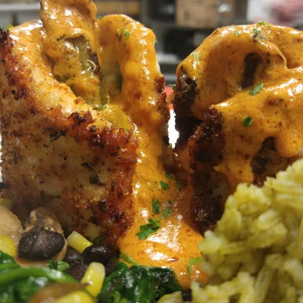 Close-up of Osorio's Latin Fusion's chicken dish, smothered in orange sauce, with rice and vegetables.